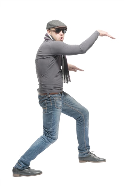 Unshaven bald man wearing a cap jeans sunglasses and a scarf dancing a strange dance Isolated