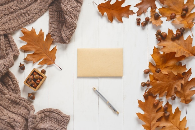 Unsigned envelope and pen on white wooden table with autumn accessories View from above