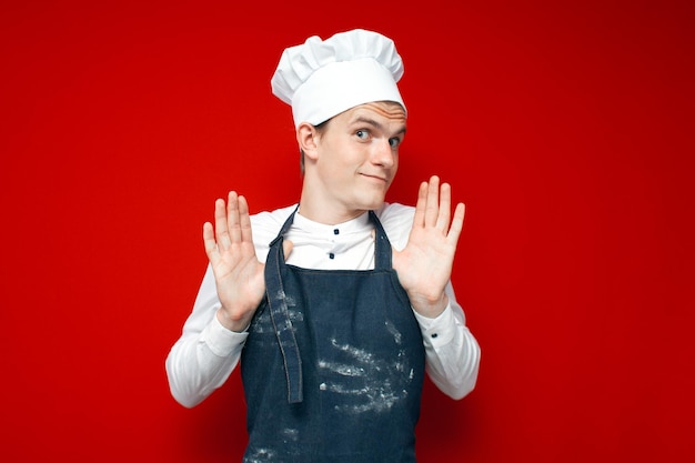 Unsure chef in uniform shrugs hands on red isolated background kitchen worker in embarrassment