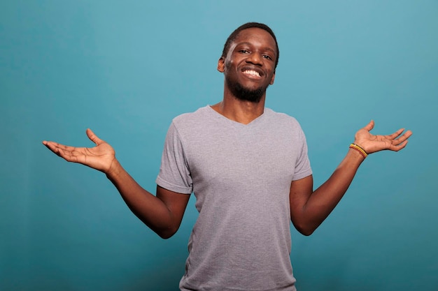 Unsure person rising shoulders and expressing confusion, doing i dont know gesture in studio. Uncertain man feeling indecisive and clueless about answer or solution. Confused guy.