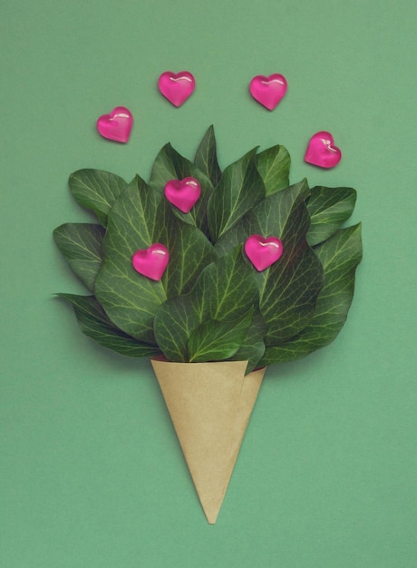 Photo an unusual bouquet with hearts and green leaves in a paper wrapper creative valentines day greeting card