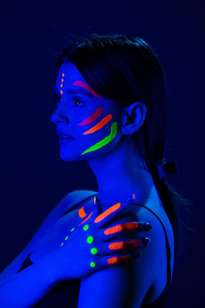 Unusual fluorescent makeup on the skin of a beautiful woman glowing under ultraviolet light