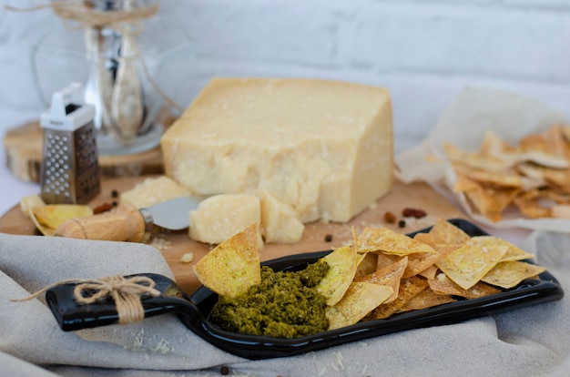 Unusual serving plate made from bottle with homemade chips and italian pesto sauce and parmesan cheese