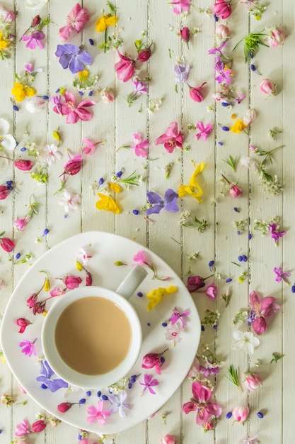 up of coffee with milk on a wooden background with small flowers good morning top view