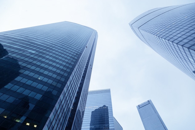 Up view of modern buildings from glass material blue colored. High houses and blue sky. High-rises buildings stretching up to heaven.