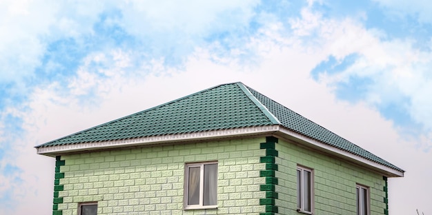 The upper part of the roof of a very neat and colorful house The roof of the house from a metal profile against the sky