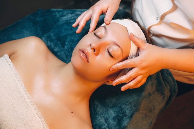 Upper view of a cute woman doing skin care treatment with hyaluronic acid by a cosmetology in a wellness resort.