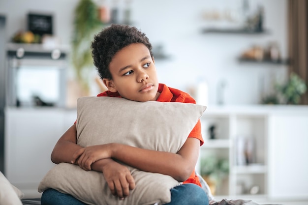 Upset. A boy with a pillow in hands looking upset