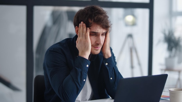 Upset businessman finding mistakes in documents in office Close up frustrated worker looking at laptop computer at home office Sad business man reading finance report at notebook indoors