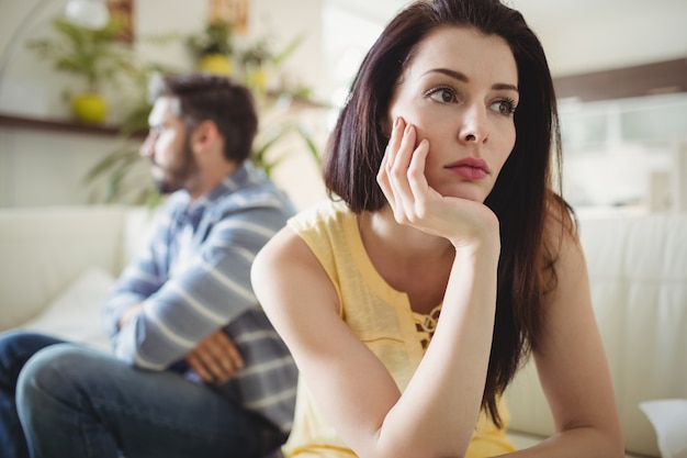 Upset couple ignoring each other on sofa