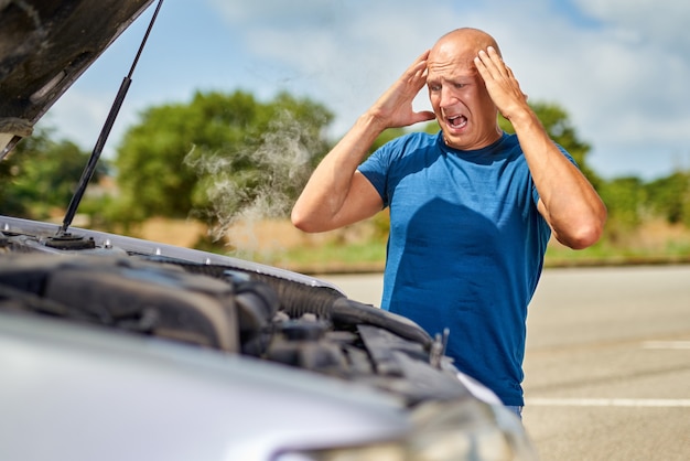 Upset driver man in front of automobile crash car collision accident in road.