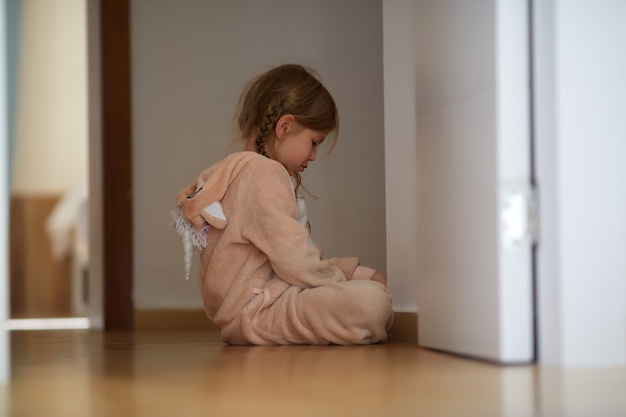 Upset girl sitting on floor near door