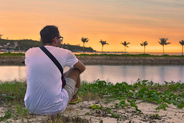 Upset man sitting at beach and watching sunset in tropics of Vietnam