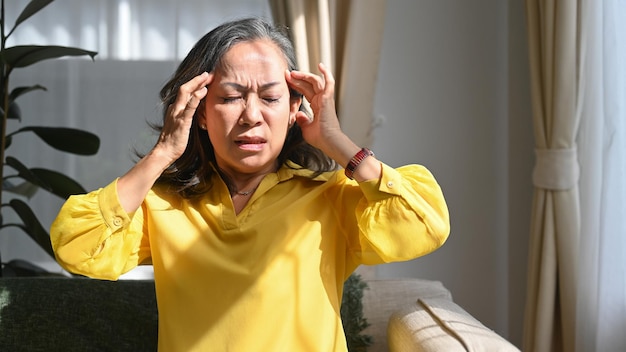 Upset mature woman touching her head suffering from head ache migraine or dizziness Age medicine health care and people concept