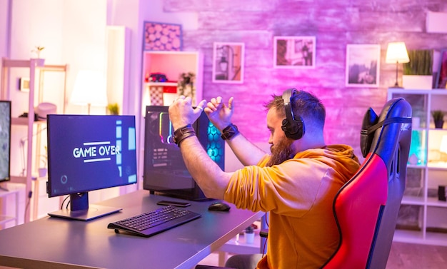 Upset professional gamer because he lost an important game. Room full of neon lights.