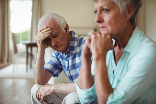 Upset senior couple relaxing on sofa