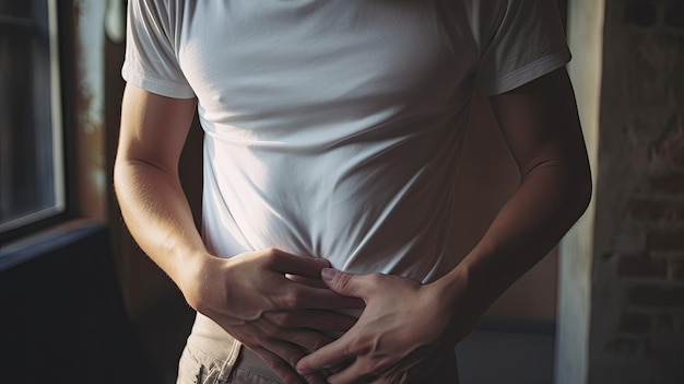 Upset unhappy young man holding his abdomen with both hands suffering from bellyache isolated on gray background