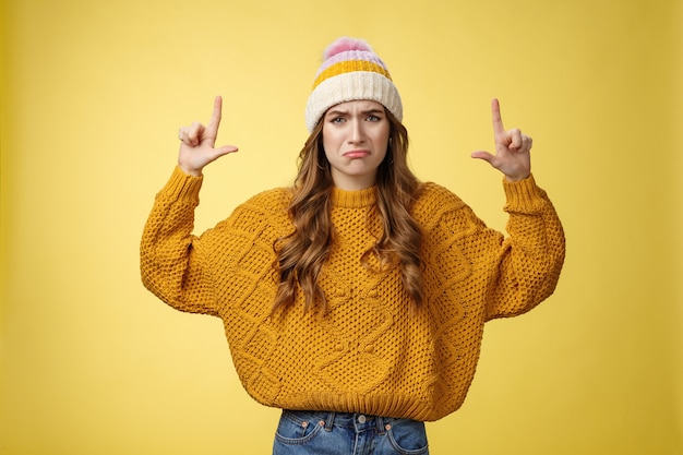 Upset whining complaining displeased cute young immature girl raise hands pointing up crying jealous regret wanna buy cool product have no money, standing sad sobbing yellow background