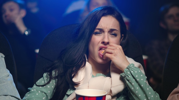 Upset woman losing time on bad film in cinema Frustrated girl watching movie