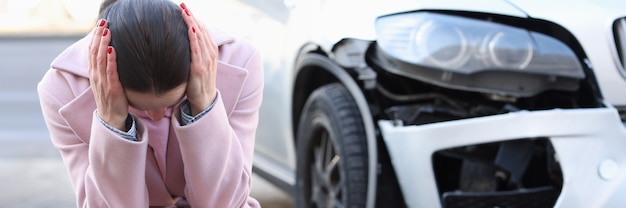 Photo an upset woman sits with her head down next to developed car road traffic accidents and