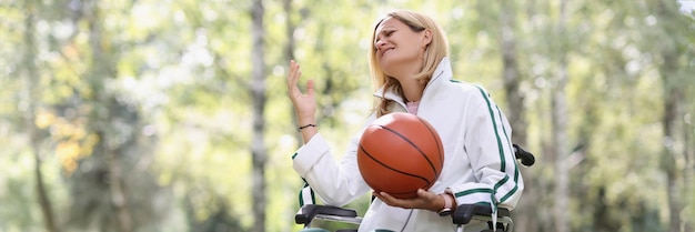 Upset woman sitting in wheelchair and holding basketball sports and disabled people concept