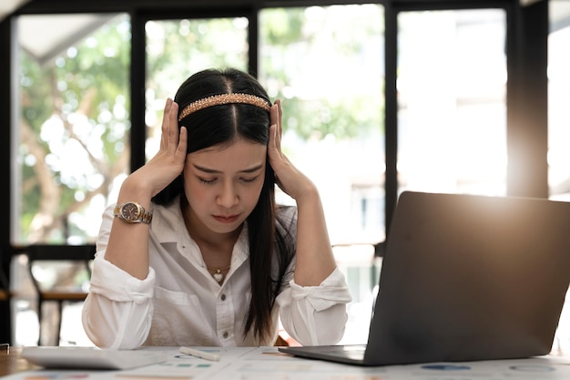 Upset woman touching head using calculator and laptop for calculating finance Frustration young housewife with headache taxing accounting statistics and credit analytic for mortgage payment