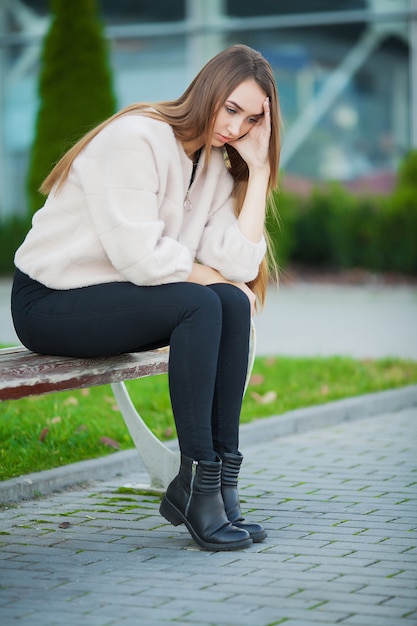 Upset woman with problems sitting on a bench