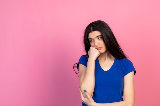 An upset young girl holding her fist to her chin and looking down High quality photo