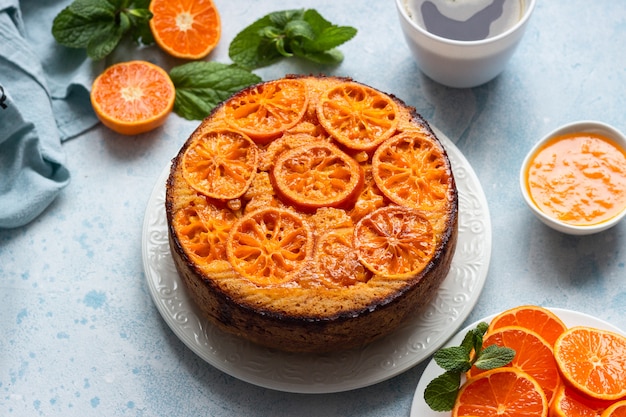 Upside down tangerine cake on a sky-blue stone or concrete background.