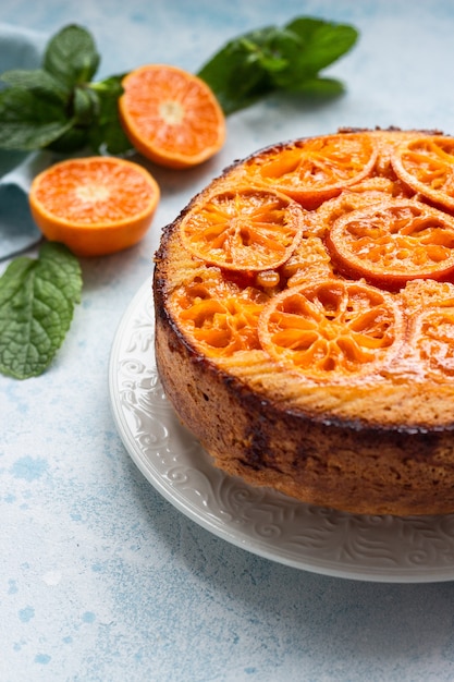 Upside down tangerine cake on a sky-blue stone or concrete background.