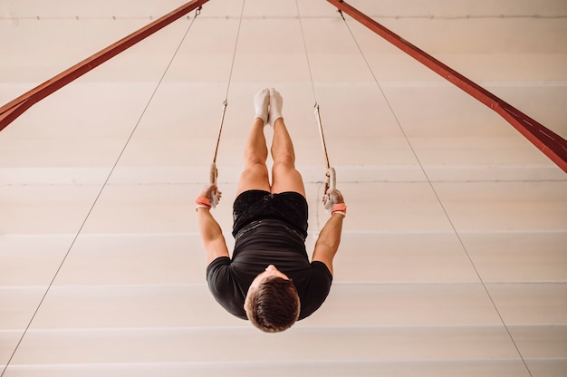 Upside down young man exercising on gymnastics rings