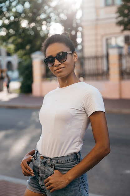 Urban afro american woman walking on the city street square on sunset