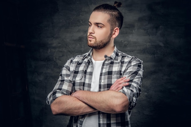 Urban bearded hipster male with crossed arms over grey background.