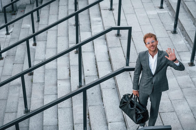 Urban beauty Young businessman in grey formal wear is outdoors in the city