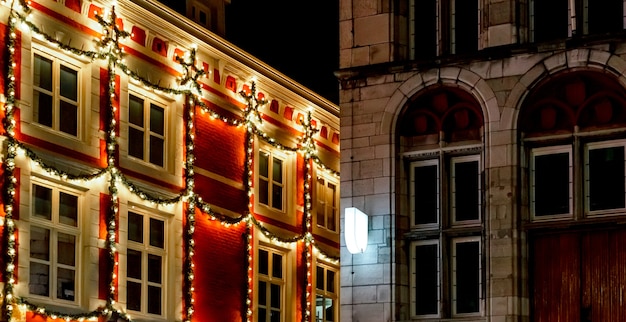 Urban Christmas facade decorations. Christmas garland lights up on window house. Festive lighting of city streets. New Year's decor. European vintage christmas.