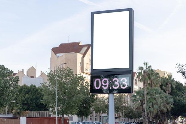 Urban digital clock post with a blank advertising panel against a cityscape ideal for promotions Vertical billboard mockup empty display Copy space for text picture