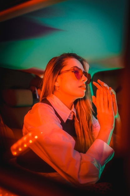 Urban photography with red and green neons in the back of a car of a young blond