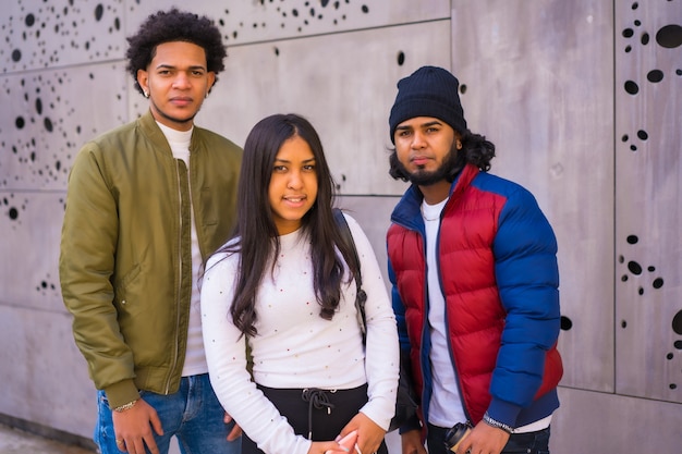 Urban style, portrait of three Latin black friends having fun in the street and talking to each other.