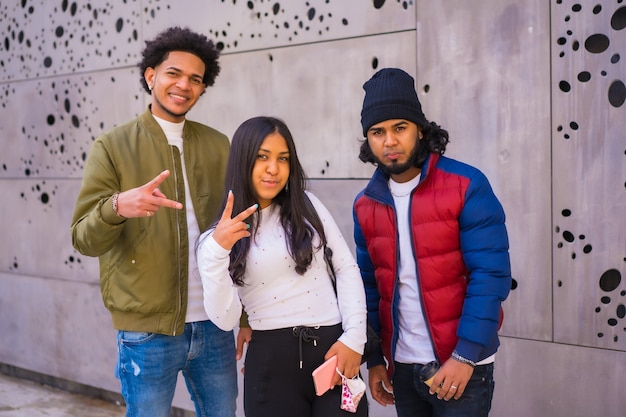 Urban style, portrait of three Latin black friends having fun in the street and talking to each other.