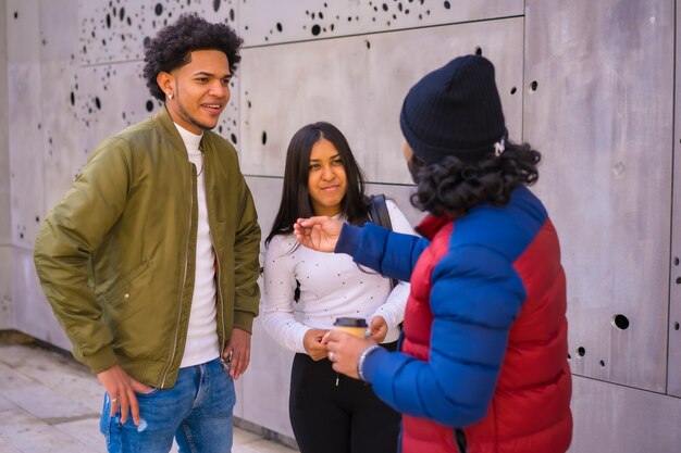 Urban style, three black Latino friends having fun in the street and talking to each other.