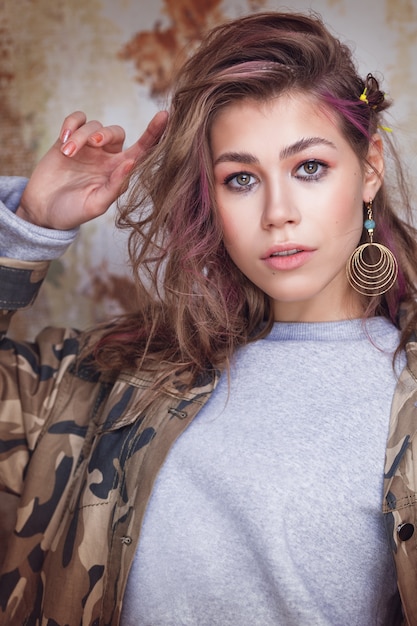 Urban trendy girl with colorful messy hair in camouflage jacket