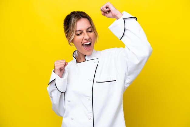 Uruguayan chef woman isolated on yellow background celebrating a victory