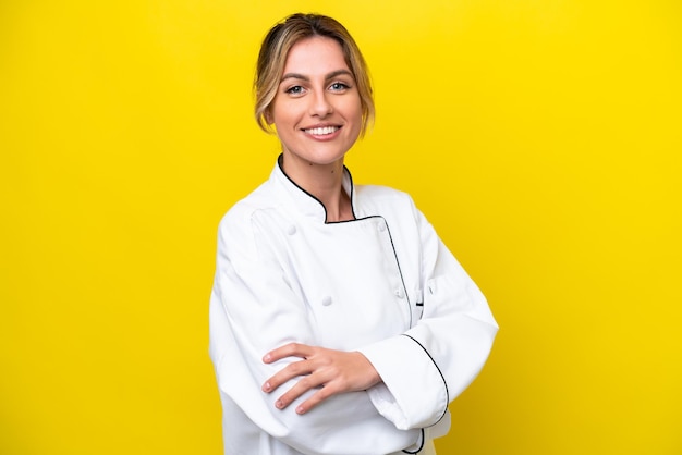 Uruguayan chef woman isolated on yellow background with arms crossed and looking forward