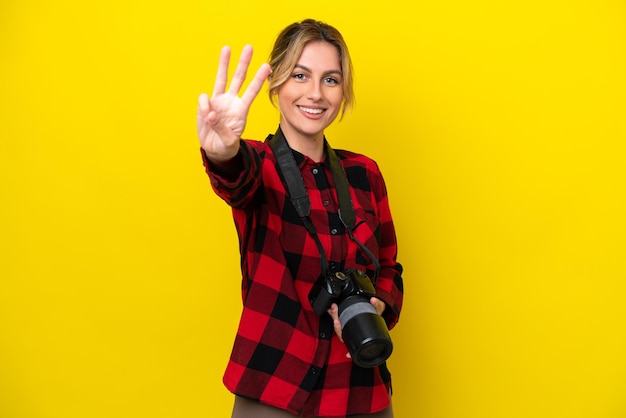 Uruguayan photographer woman isolated on yellow background happy and counting three with fingers