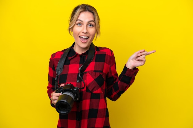 Uruguayan photographer woman isolated on yellow background surprised and pointing side