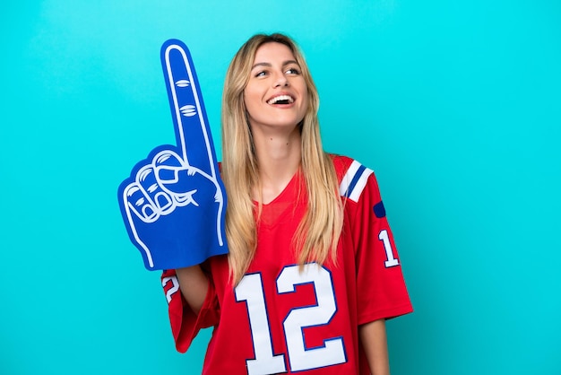 Uruguayan sports fan woman isolated on blue background laughing