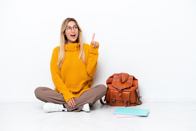 Uruguayan student woman sitting one the floor isolated on white background thinking an idea pointing the finger up