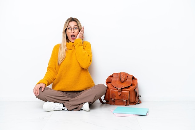 Uruguayan student woman sitting one the floor isolated on white background with surprise and shocked facial expression