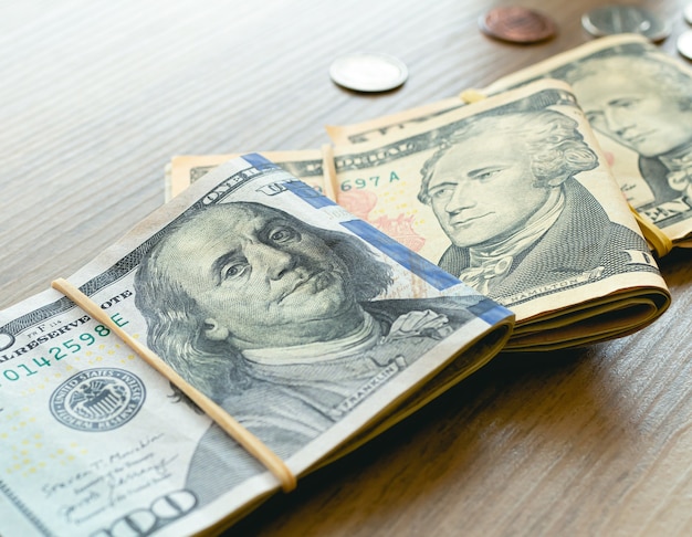 US dollar banknotes and coins on wooden furniture in closeup photography