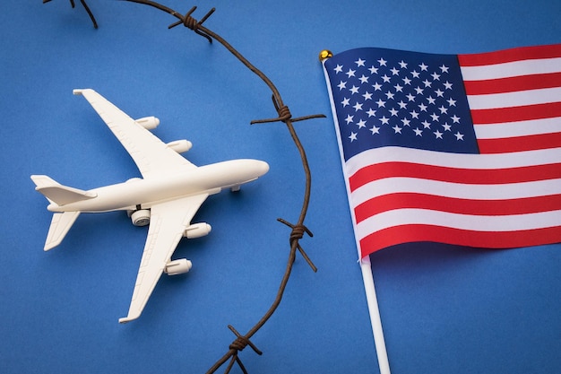 USA closed airspace concept toy plane barbed wire and flag on blue background